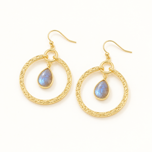 Gold-tone circle and teardrop earrings on a plain warm-white background