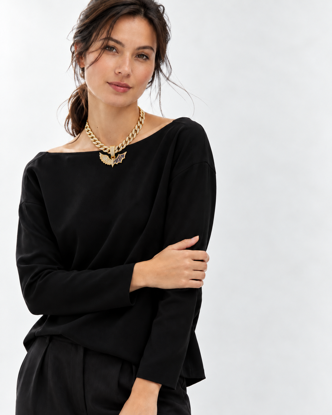 Gold-tone two wings necklace worn with a black wide-neck top
