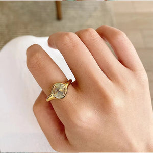 Gold-tone oval sunburst ring worn close-up on a finger