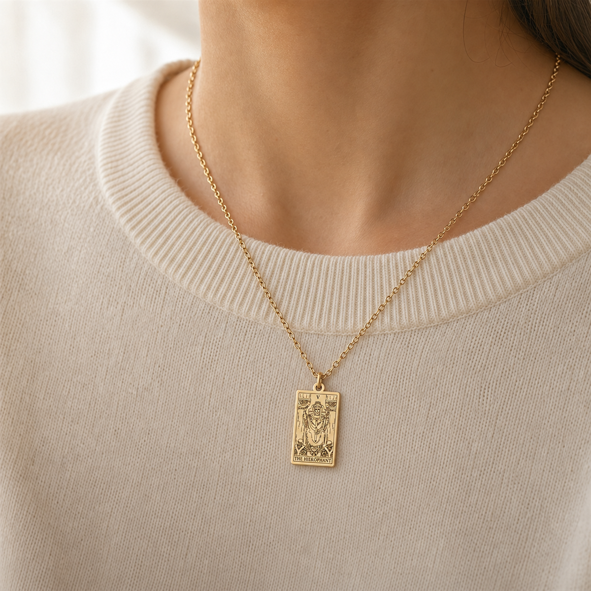 Gold The Hierophant tarot-card pendant necklace worn over a cream knit top.