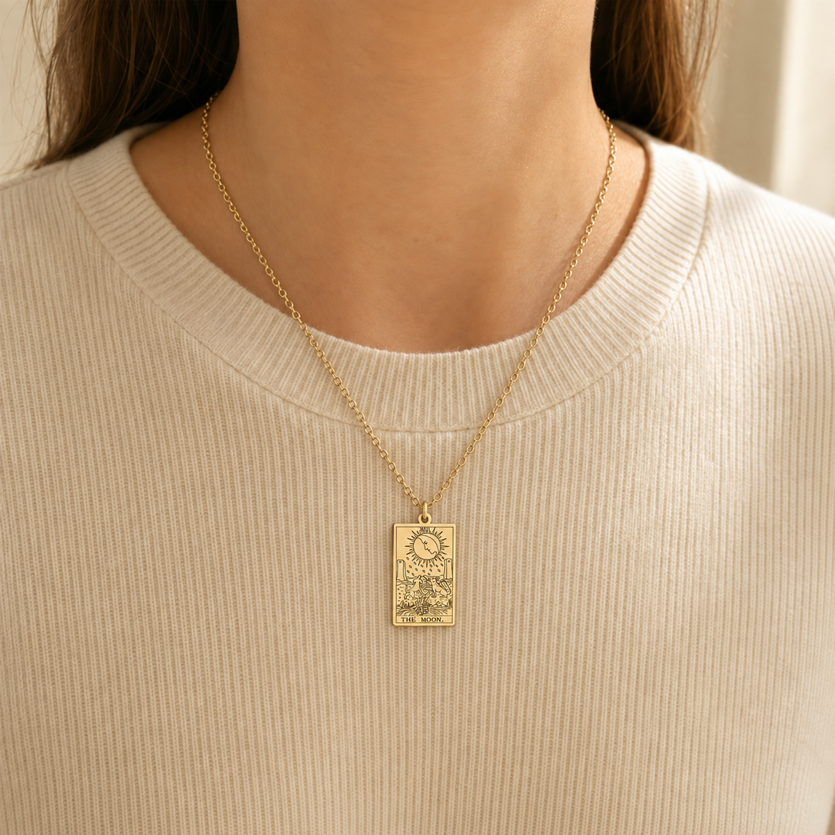 Gold The Moon tarot-card pendant necklace worn over a cream knit top.