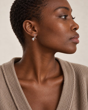 Silver-tone leaf drop earrings worn at natural scale; AI-generated brand photograph