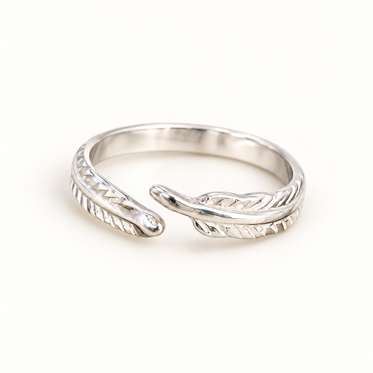 Silver-tone twin feather ring on a warm-white background