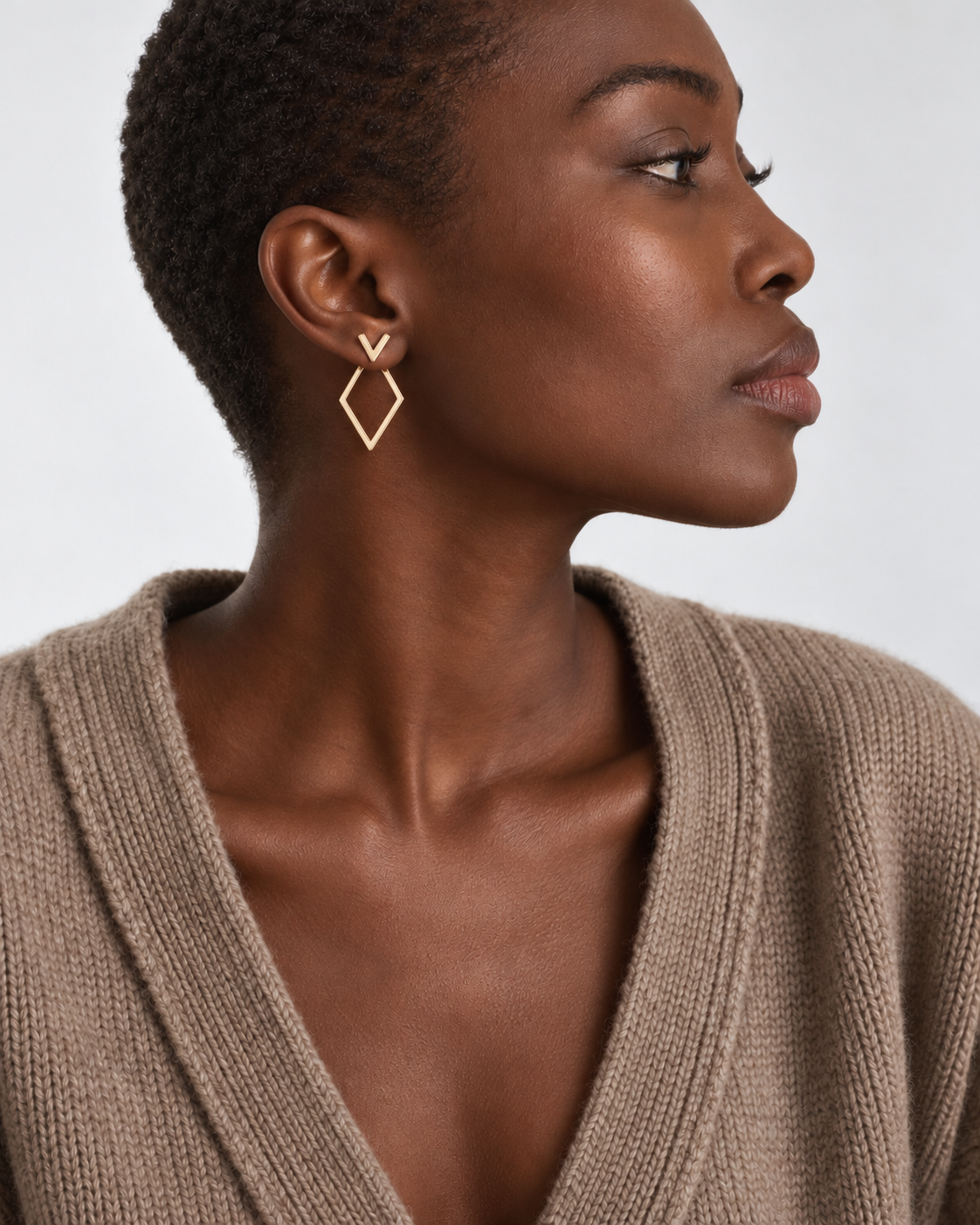 Gold-tone geometric jacket earrings worn with neutral clothing