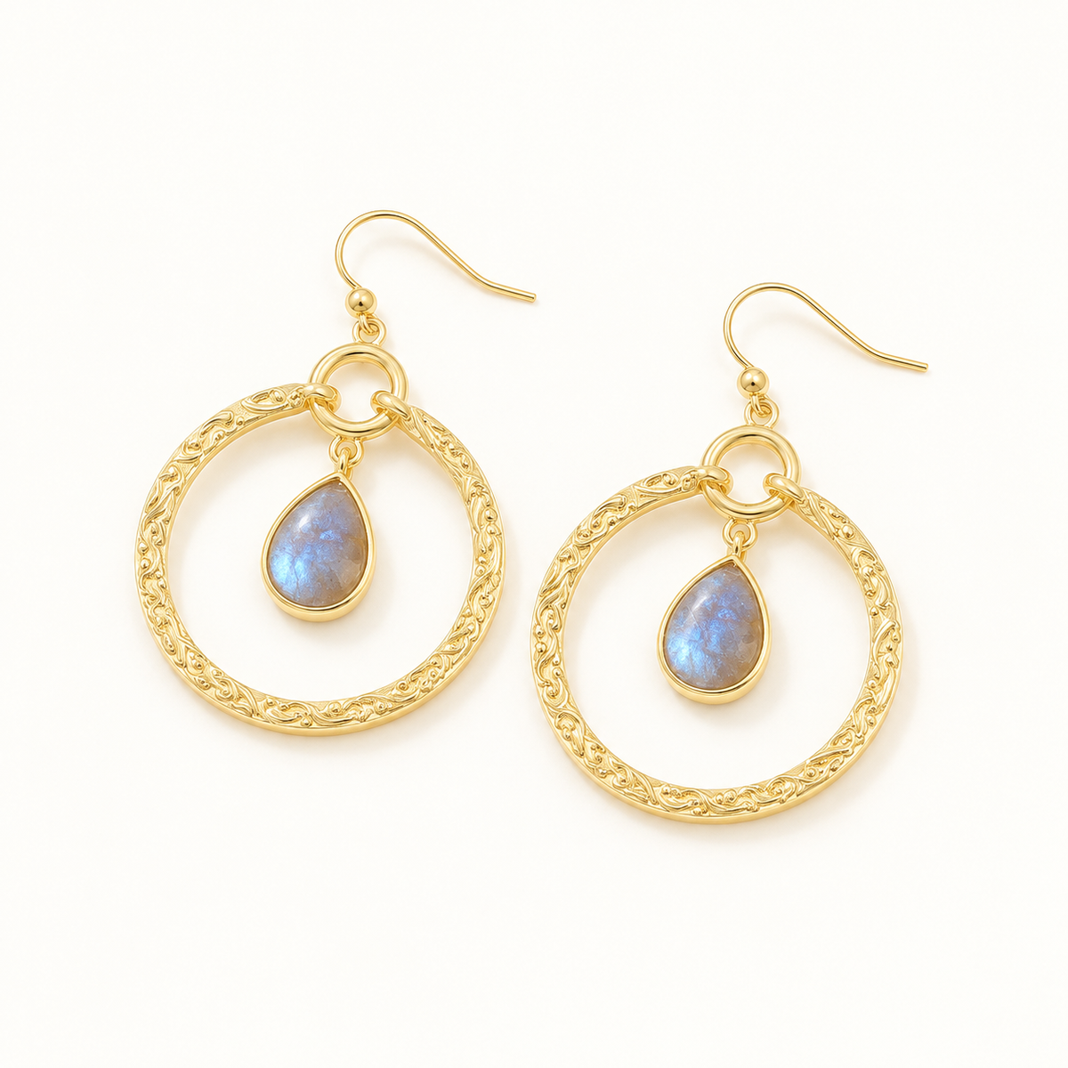 Gold-tone circle and teardrop earrings on a plain warm-white background