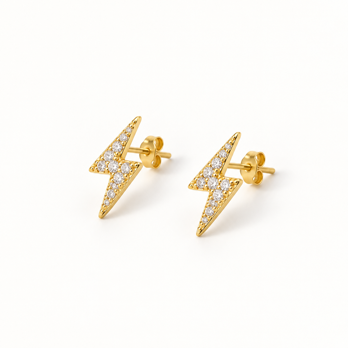 Gold-tone lightning stud earrings on a warm-white background