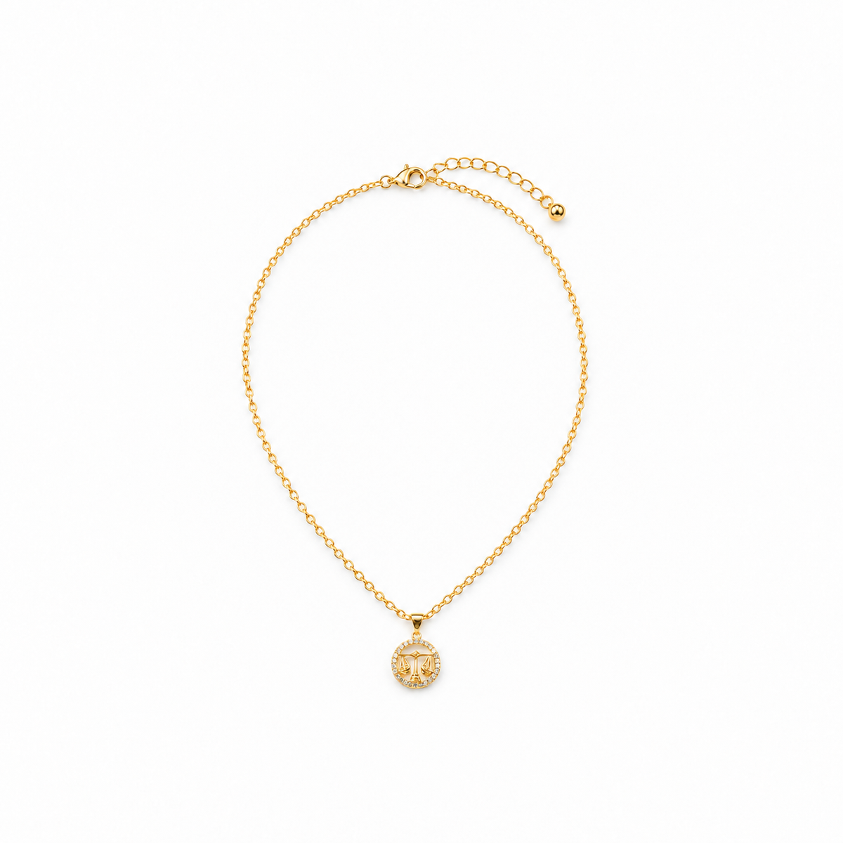 Gold-tone libra medallion necklace on a warm-white background