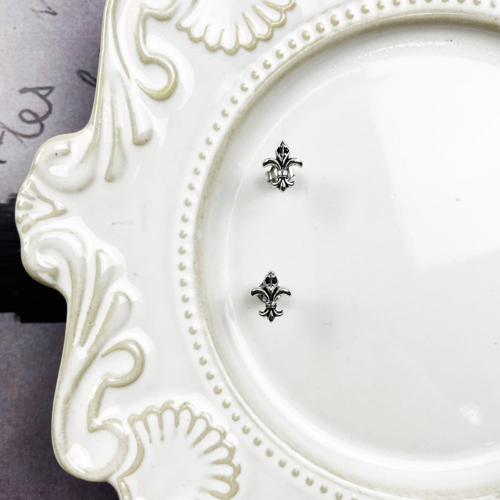Silver-tone fleur-de-lis earrings in a detail product view