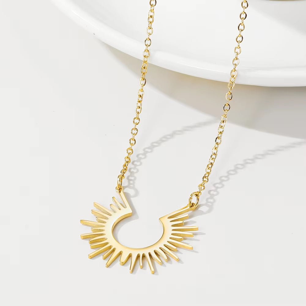 Gold-tone sun necklace arranged beside a pale dish
