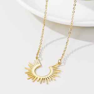 Gold-tone sun necklace arranged beside a pale dish