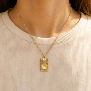 Gold The Lovers tarot-card pendant necklace worn over a cream knit top.