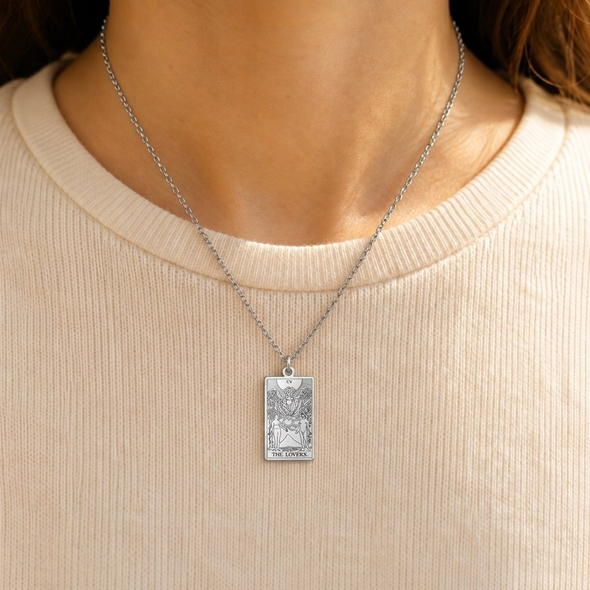 Silver The Lovers tarot-card pendant necklace worn over a cream knit top.