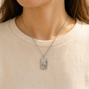 Silver The Star tarot-card pendant necklace worn over a cream knit top.