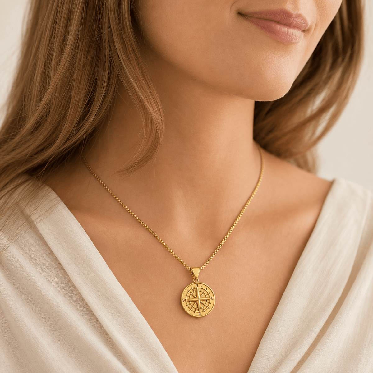 Model wearing a gold-tone compass-pattern pendant necklace with a pale neckline