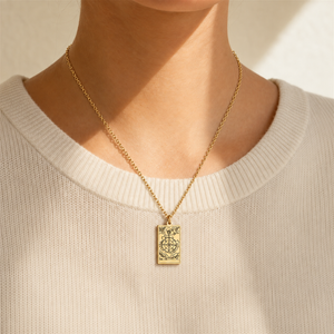 Gold Wheel of Fortune tarot-card pendant necklace worn over a cream knit top.